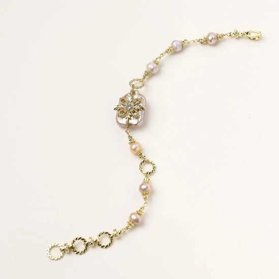 Gold-plated bracelet with pink baroque pearl centerpiece, floral connector, and freshwater pearls