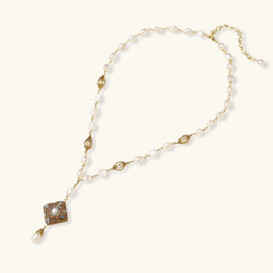 Y-shaped necklace with freshwater pearls, gold filigree stations, and ornate diamond-shaped centerpiece with pearl drop
