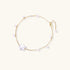 Delicate gold chain bracelet with baroque pearl centerpiece and small freshwater pearls on cream background.