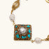 Gold-plated bracelet with baroque centerpiece, turquoise stones, freshwater pearls, and ornate chain links on cream background.