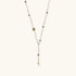 Y-shaped gold-plated necklace with white and gray freshwater pearls on cream background, showing adjustable drop design.