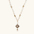 Y-shaped necklace with freshwater pearls, gold filigree stations, and ornate diamond-shaped centerpiece with pearl drop