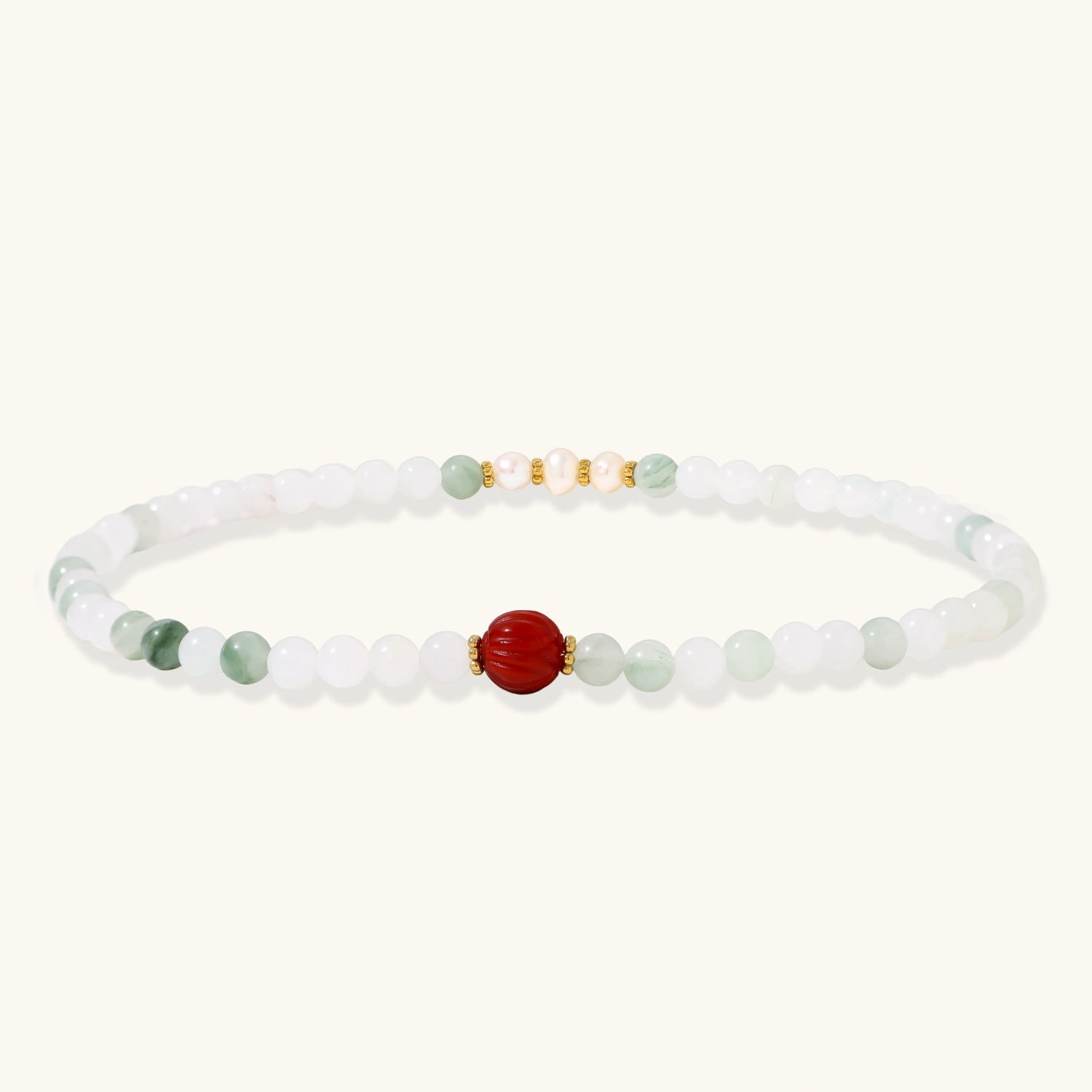 Three layered white beaded bracelets with carved orange agate lotus centerpiece and freshwater pearls on cream background.
